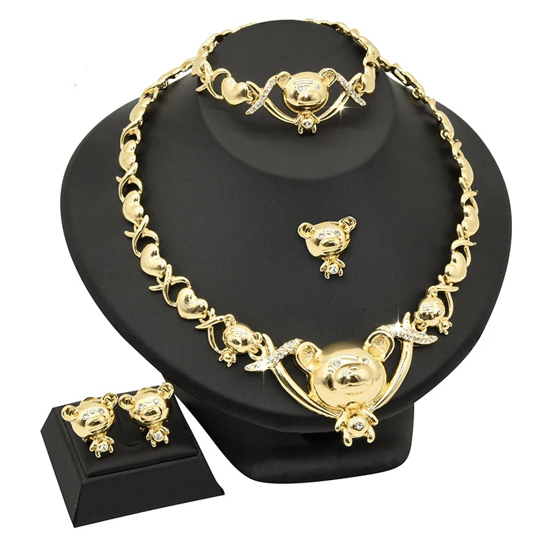 A set of 18K gold heart crystal jewelry including a necklace and earrings displayed on a black stand.