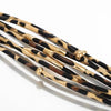 Braçoles en cuir tube à motif léopard bohème avec accents dorés.