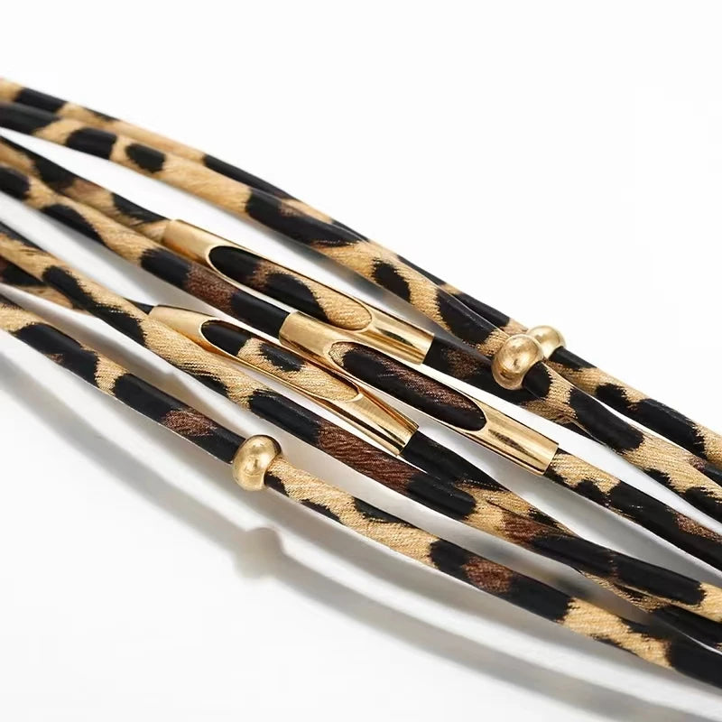 Braçoles en cuir tube à motif léopard bohème avec accents dorés.