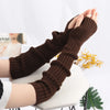 A pair of brown knitted fingerless gloves are shown being held up against a white background.