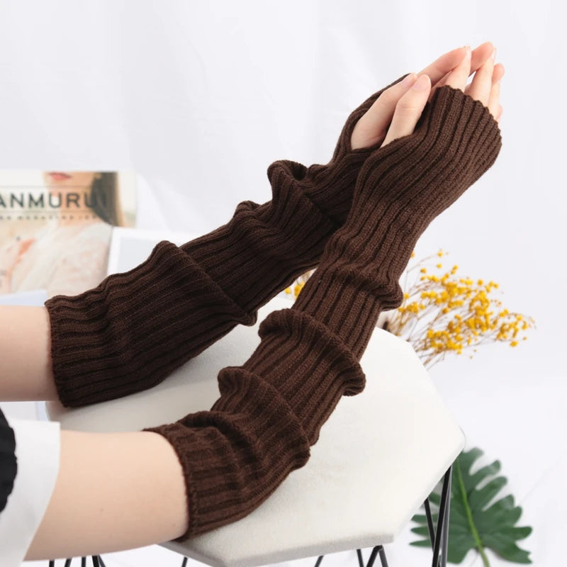 A pair of brown knitted fingerless gloves are shown being held up against a white background.