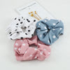 Three knitted hair scrunchie headbands in white, blue, and pink with polka dots displayed on a white background.
