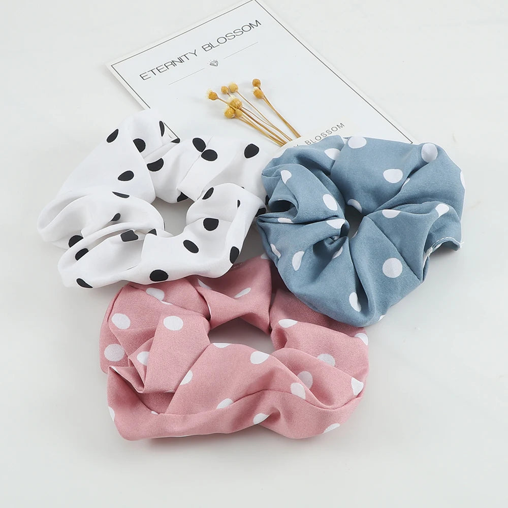 Three knitted hair scrunchie headbands in white, blue, and pink with polka dots displayed on a white background.