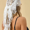A woman shows the back of her head and hair, wearing a sheer white floral lace scarf and headscarf set.