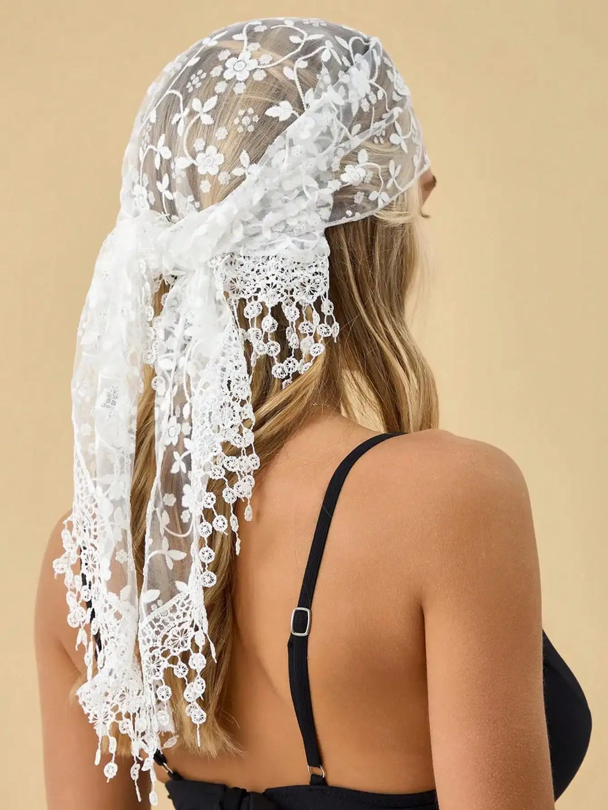 A woman shows the back of her head and hair, wearing a sheer white floral lace scarf and headscarf set.