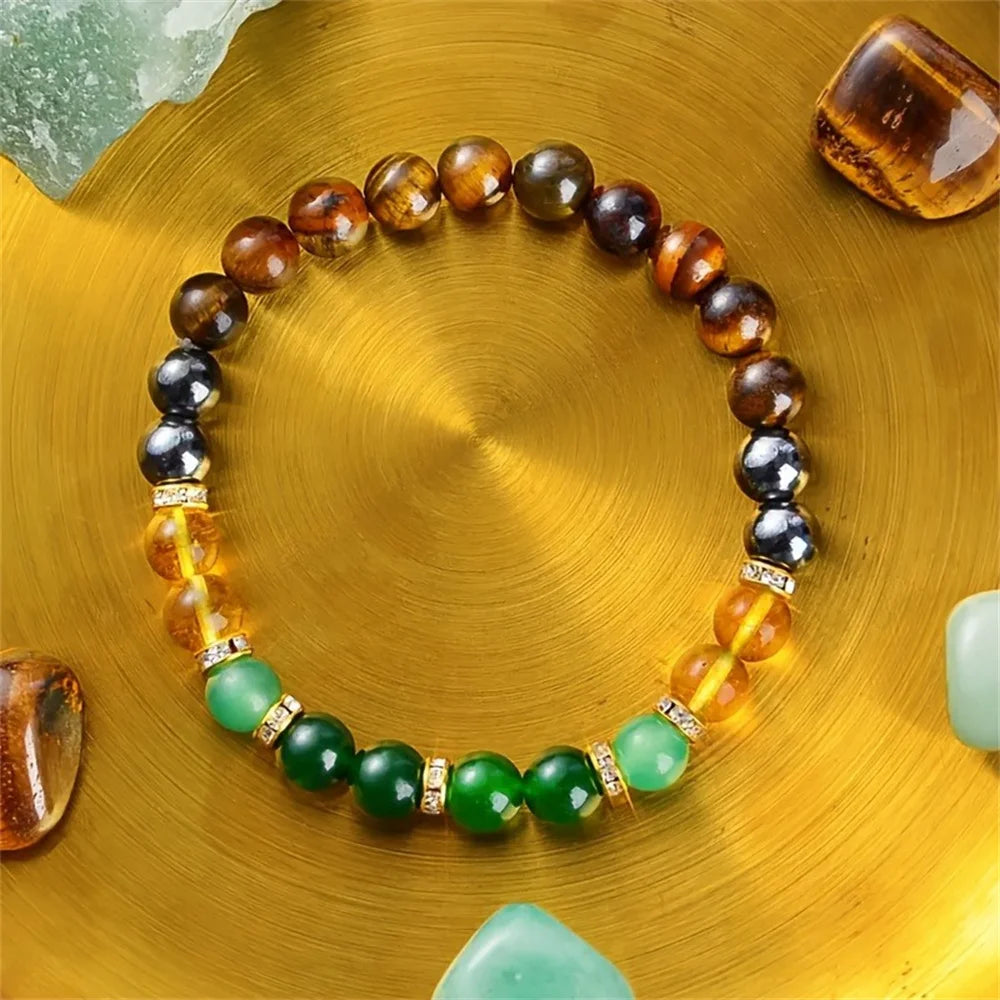 A bracelet made of citrine and tiger's eye stones is displayed on a golden surface.