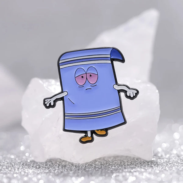 A blue cartoon enamel pin shaped like a wizard or robe is displayed on a white rock.