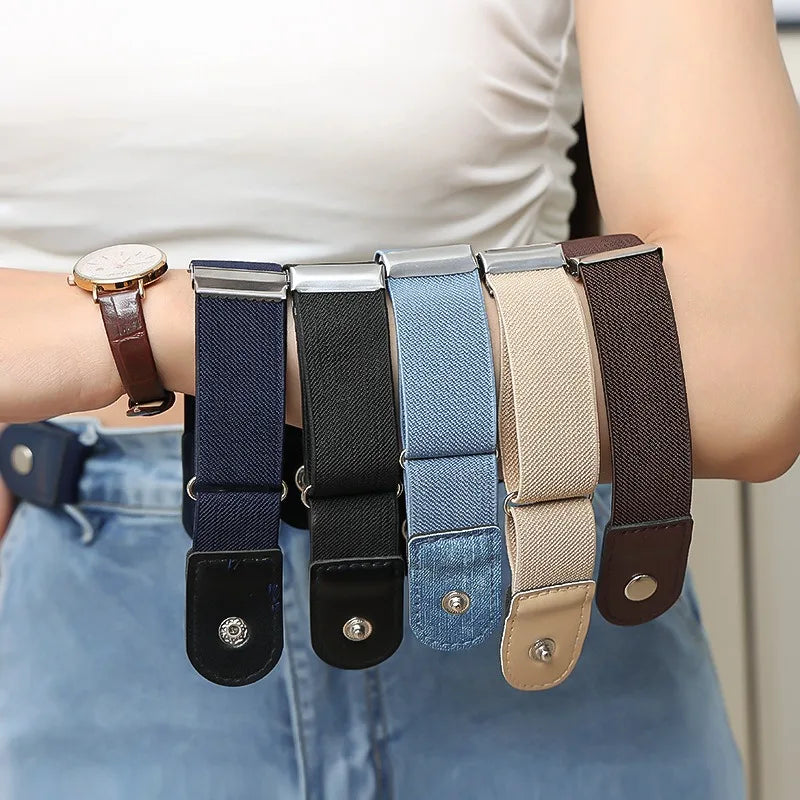 A close-up of several buckle-free elastic casual belts in various colors and materials being held by a person's hand.