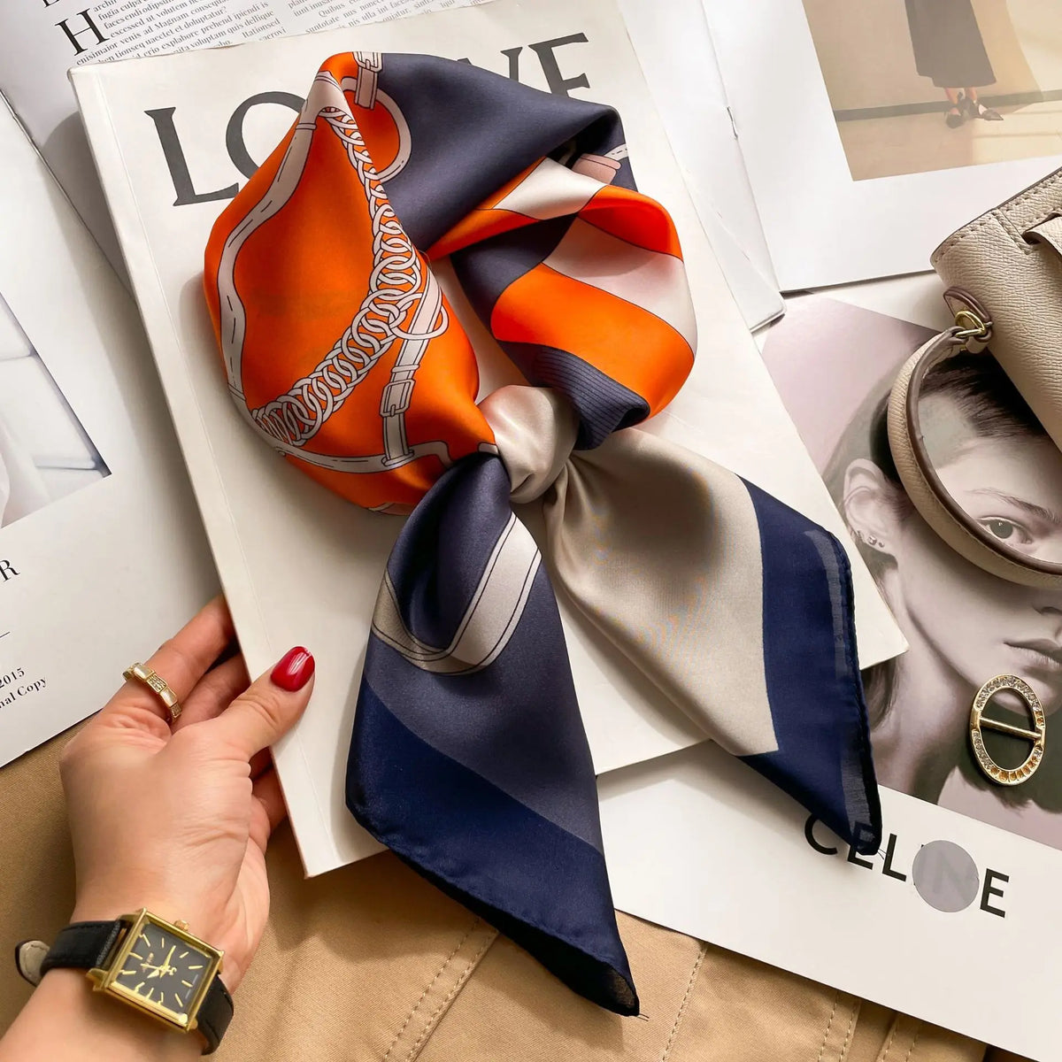 A silk scarf tied in a bow, featuring orange and navy stripes, displayed on a magazine page.