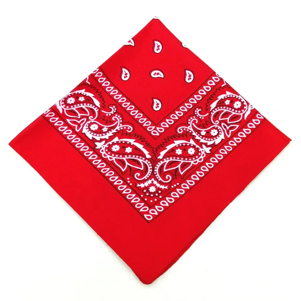 A red bandana featuring white paisley and floral patterns, used as a headband or wrist wrap.