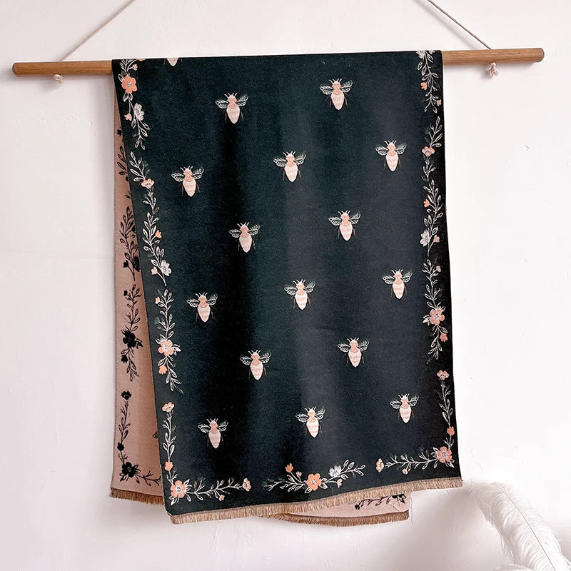 A dark green pashmina shawl with a floral print featuring small pink and white bees.