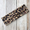 Diadema deportiva impermeable con estampado de leopardo marrón y negro sobre una superficie de madera clara.