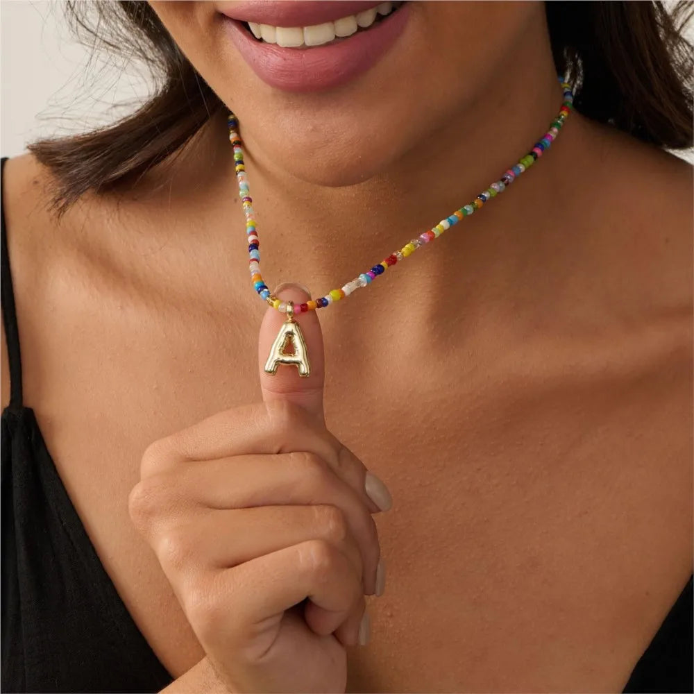 Primer plano de una mujer vistiendo un collar de cuentas con una letra inicial en el cuello.