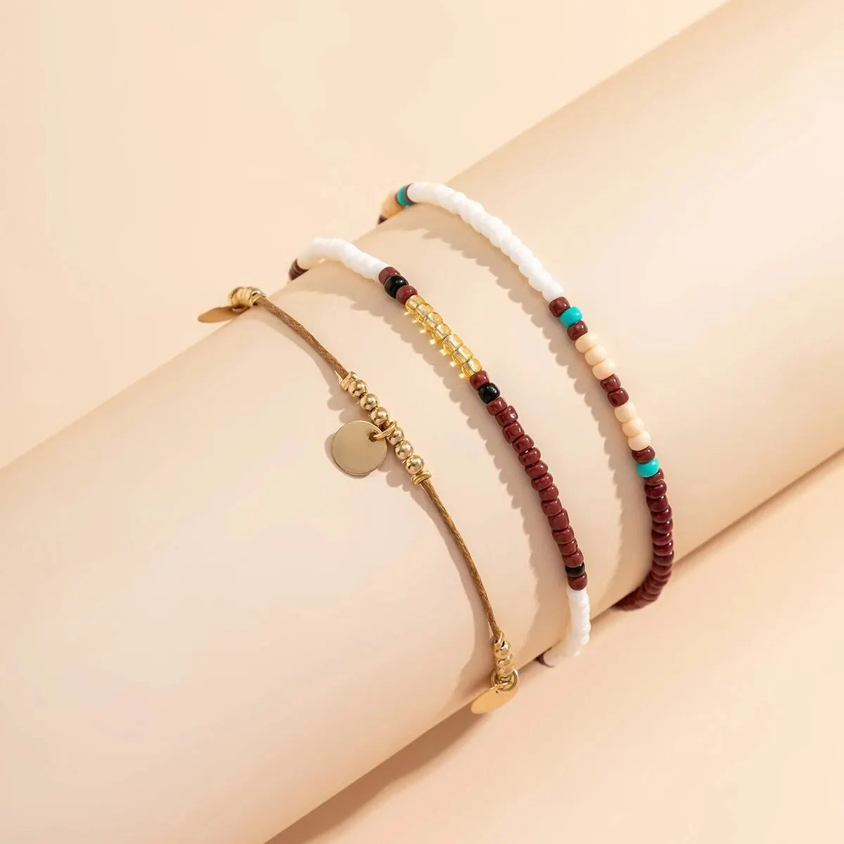 A set of bohemian sequin rice bead anklets worn on a person's wrist.