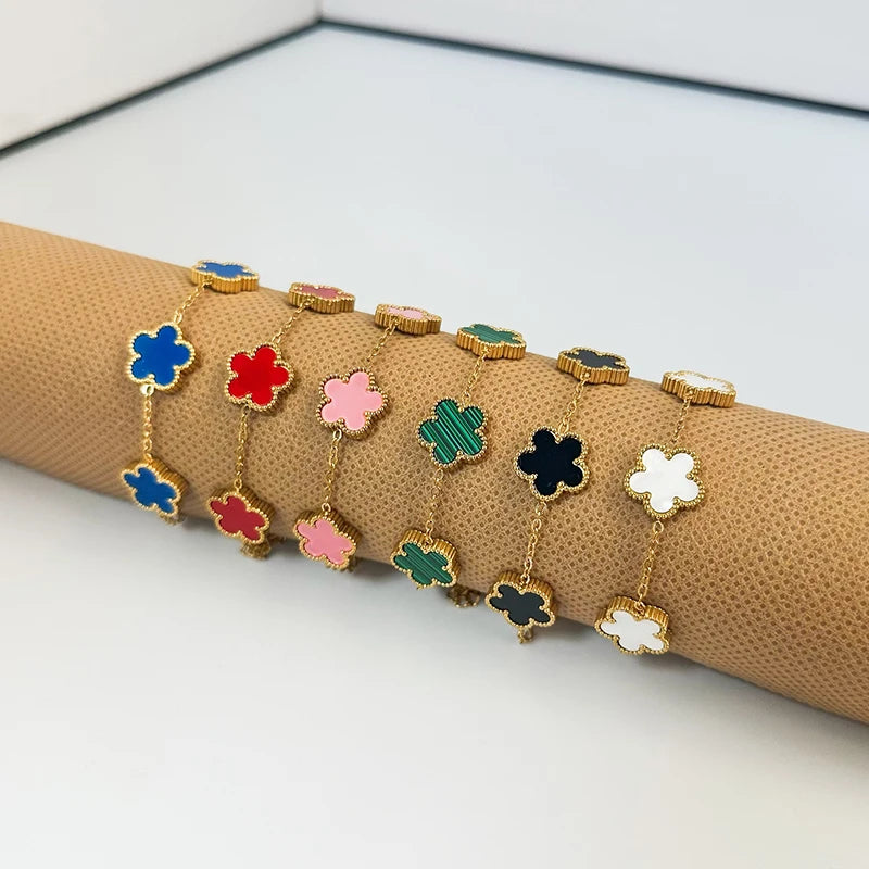 A line of gold plated stainless steel double-sided petal bracelets in various colors like blue, red, pink, and green, display