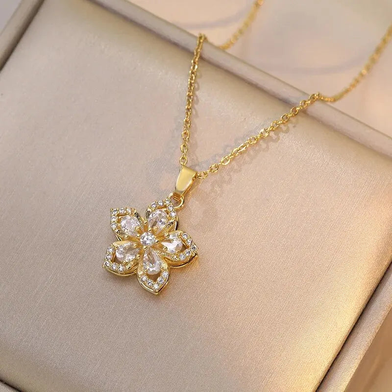 Collier en or avec pendentif de fleur zircon sur une boîte beige clair.