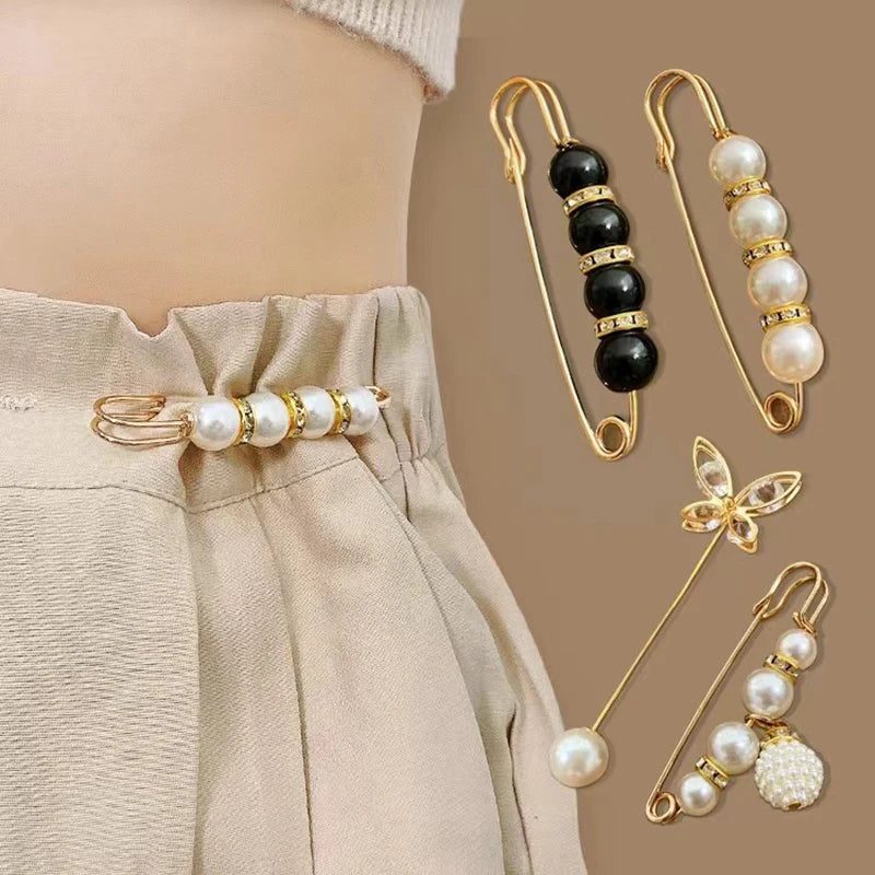 Gold-toned heavy duty pearl safety pins with black beads and a floral charm displayed against light beige fabric.