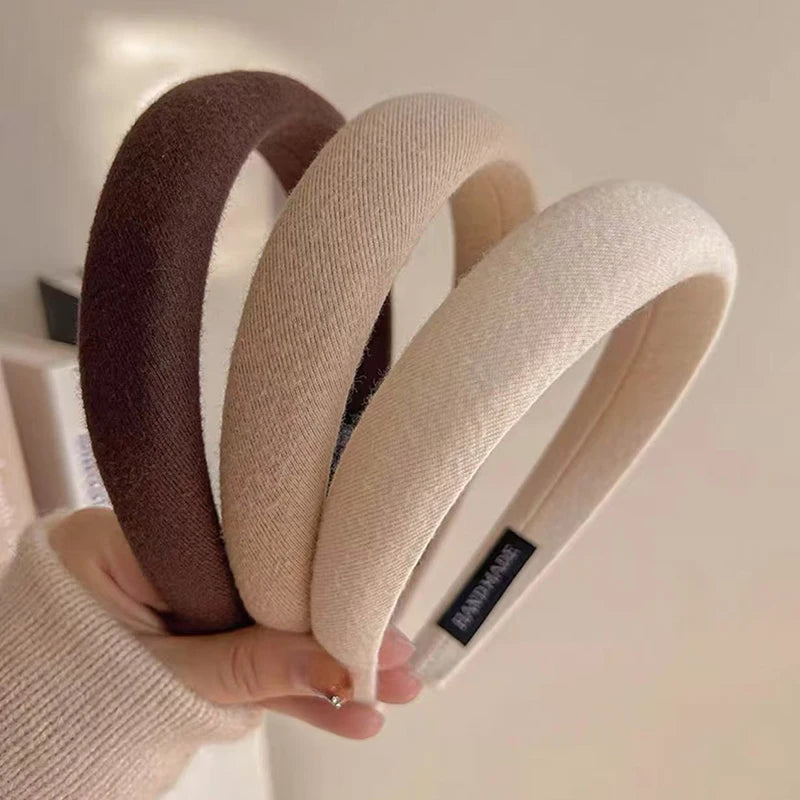 Une main tient un bandeau pour les cheveux épaissi, de couleur café, montrant sa texture et sa forme.