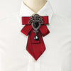A red silk tie with black diamond embellishments tied in a bow, worn against a white dress shirt.