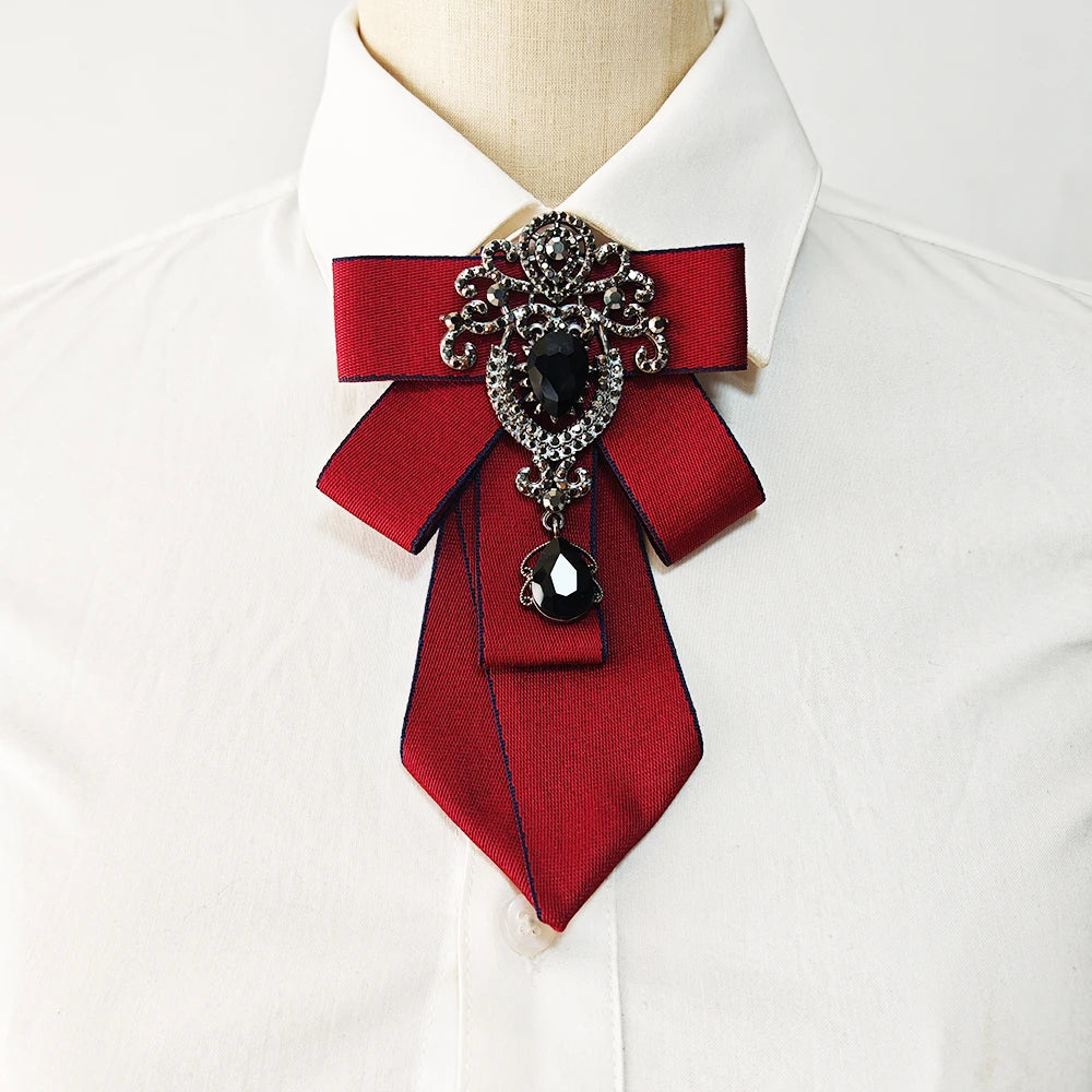 A red silk tie with black diamond embellishments tied in a bow, worn against a white dress shirt.