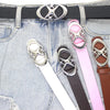 A close-up of a denim jean pocket featuring a silver moon star buckle belt and several colored leather straps.