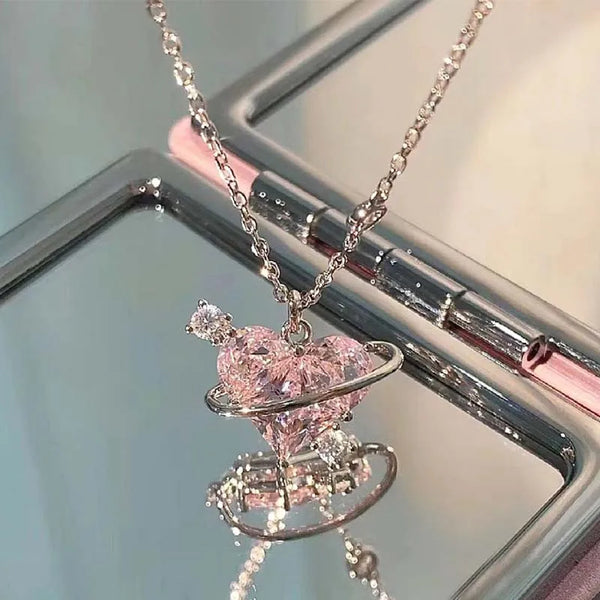 A delicate pink heart necklace featuring zircon stones displayed on a silver hanger.