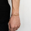 A close-up of a stainless steel twisted chain bracelet worn on a wrist against a light background.