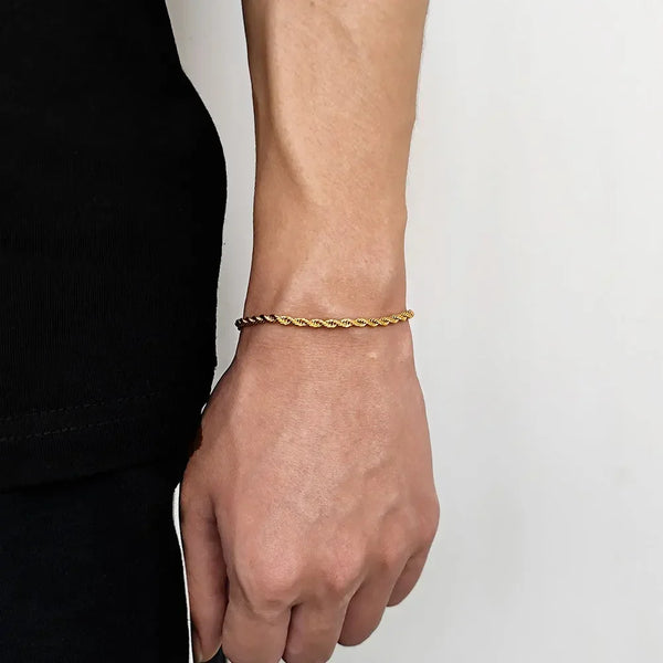 A close-up of a stainless steel twisted chain bracelet worn on a wrist against a light background.
