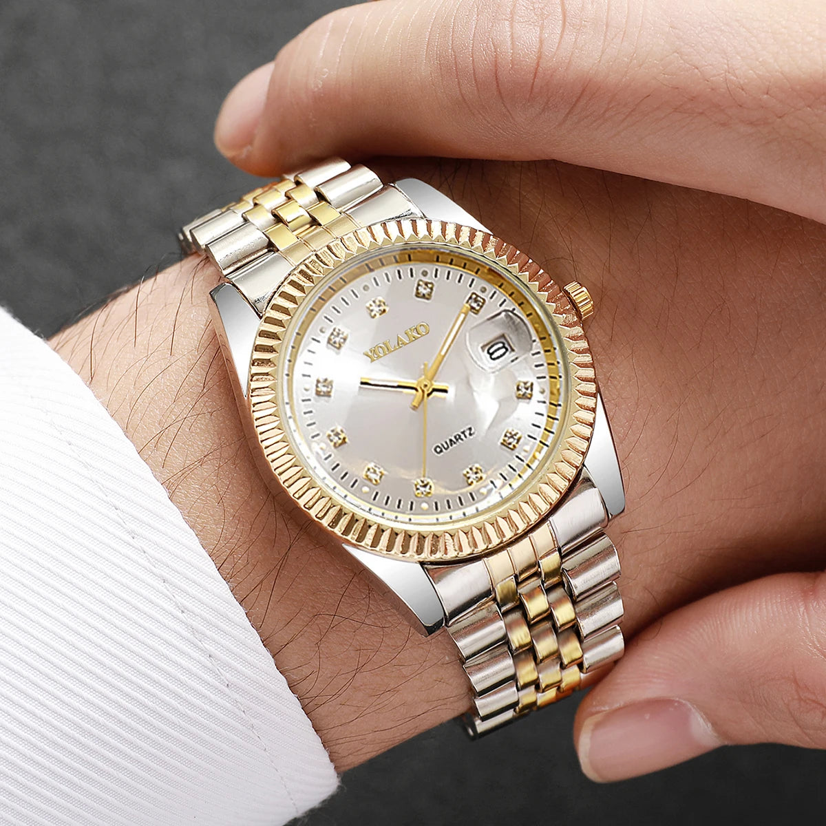 A close-up of a silver and gold rhinestone quartz wristwatch worn on a person's wrist.