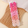 A display of pink and peach handmade ribbon bow hair clips for kids arranged on a wooden board.