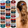 A set of five satin hair scrunchies in various shades of pink, blue, green, and brown are displayed against a light backgroun