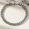 A silver multi-chain stainless steel anklet laid on a light textured surface.