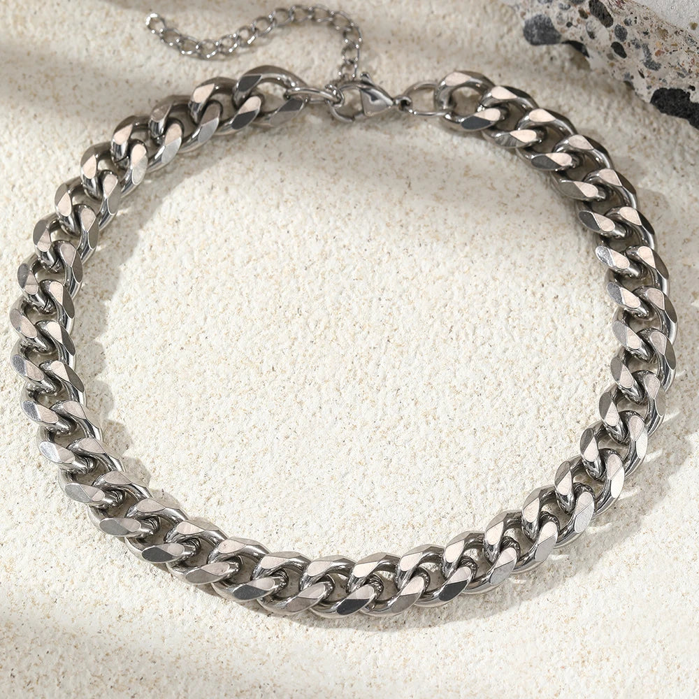A silver multi-chain stainless steel anklet laid on a light textured surface.
