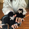 Una persona vistiendo guantes de punto negros sin dedos con patrones de estrellas plateadas, sentada en una silla.