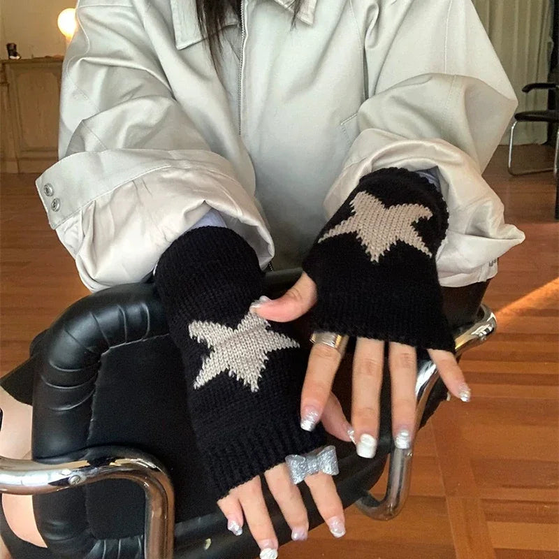 Una persona vistiendo guantes de punto negros sin dedos con patrones de estrellas plateadas, sentada en una silla.