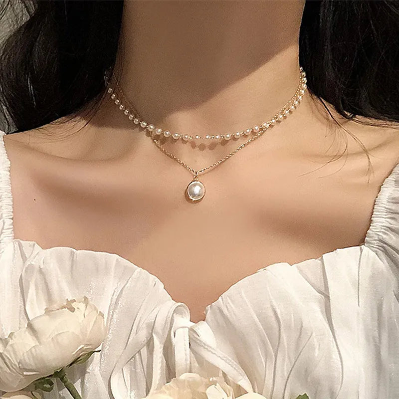 Gros plan d'une femme portant un délicat collier en or avec de petites perles et un charm de perle en goutte