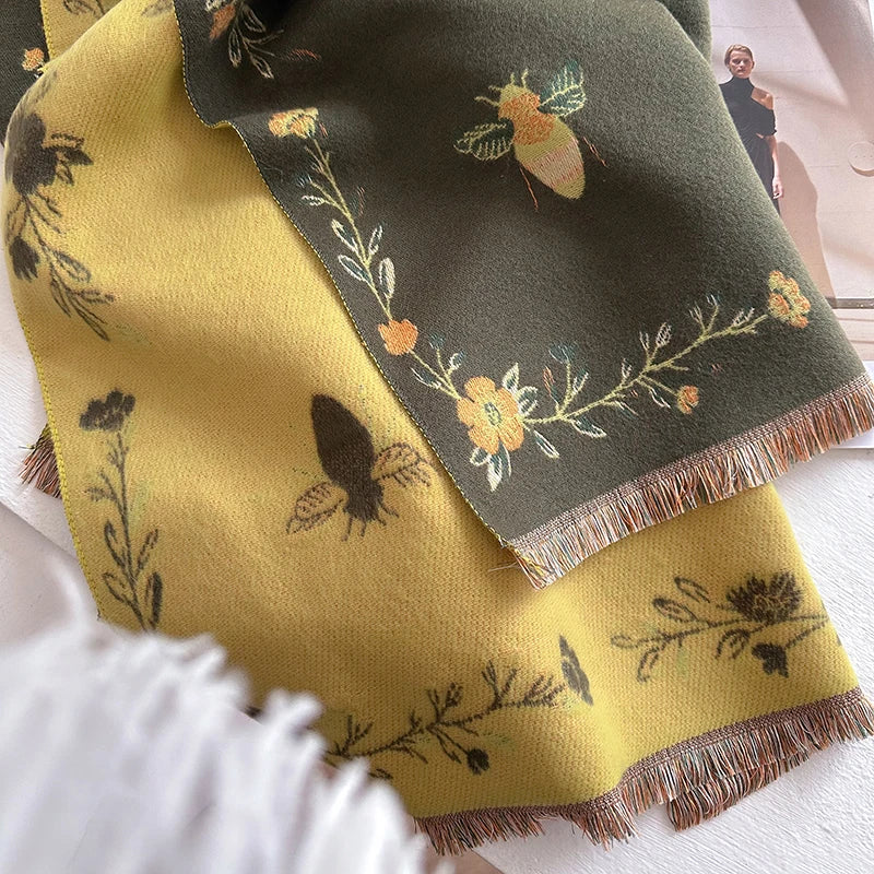 A yellow pashmina shawl with a dark green floral print featuring bee motifs and fringed edges.