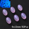 A collection of translucent purple glow-in-the-dark acrylic beads scattered on a black surface.