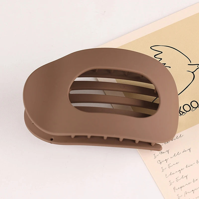 A brown flat circular hair clip set with multiple slots is shown against a light background.