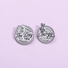 A silver enamel lapel brooch featuring a design with the text Have The Day You Deserve and a hand sign for energy.
