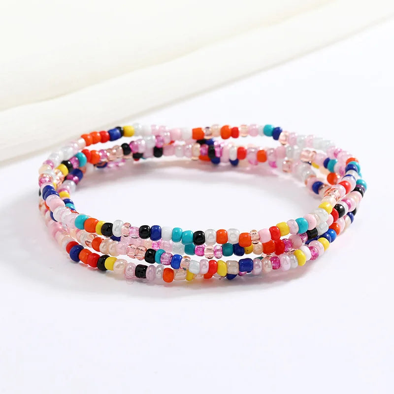 Una pulsera hecha de cuentas translúcidas y coloridas en tonos rosa, azul y rojo.