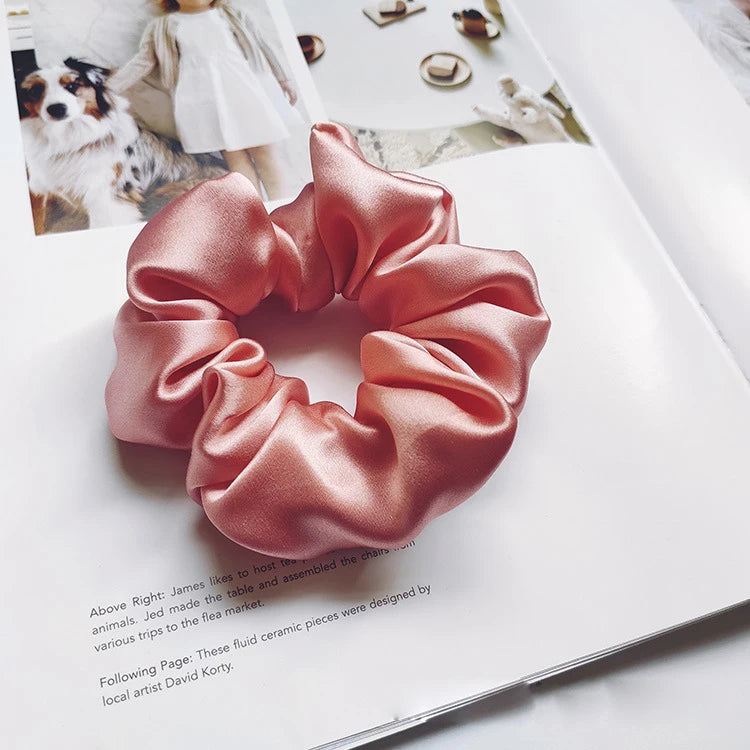 Un lazo para el pelo de seda rosa se muestra en una página blanca junto a texto que describe a la artista.