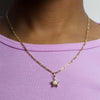 Gold plated butterfly key pendant charm necklace worn against a light purple shirt
