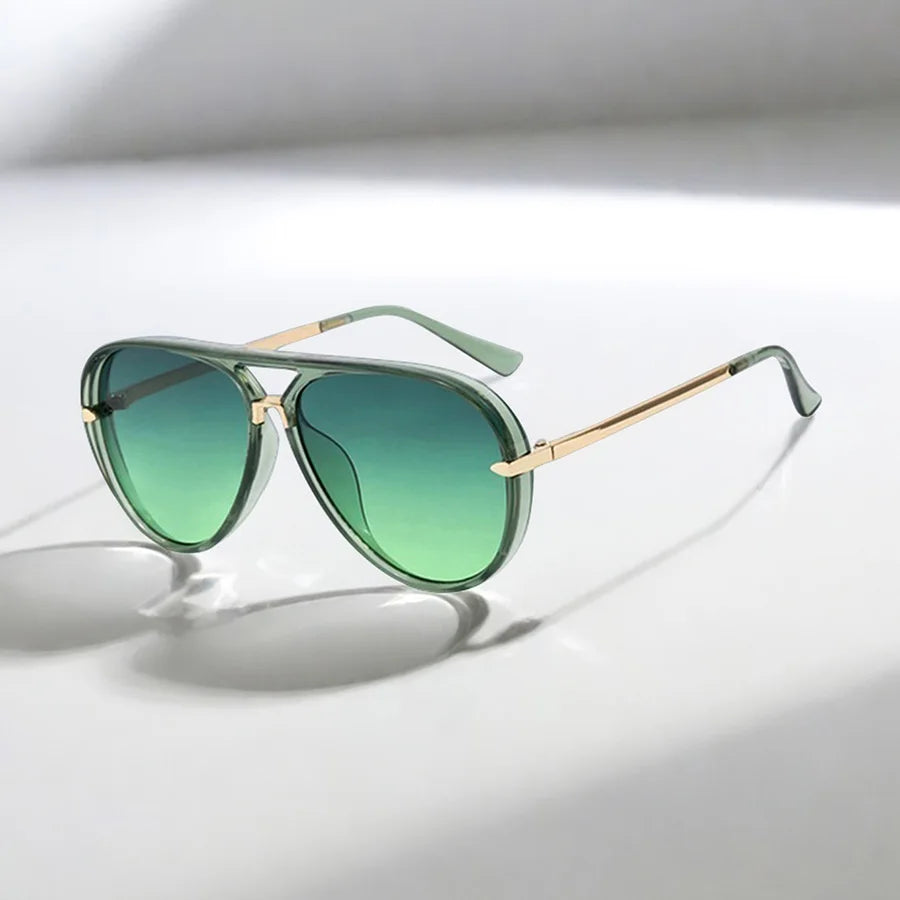 Retro large frame green fashion sunglasses with gold accents resting on a white surface.
