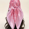 A pink floral satin shawl tied around a person's dark hair.