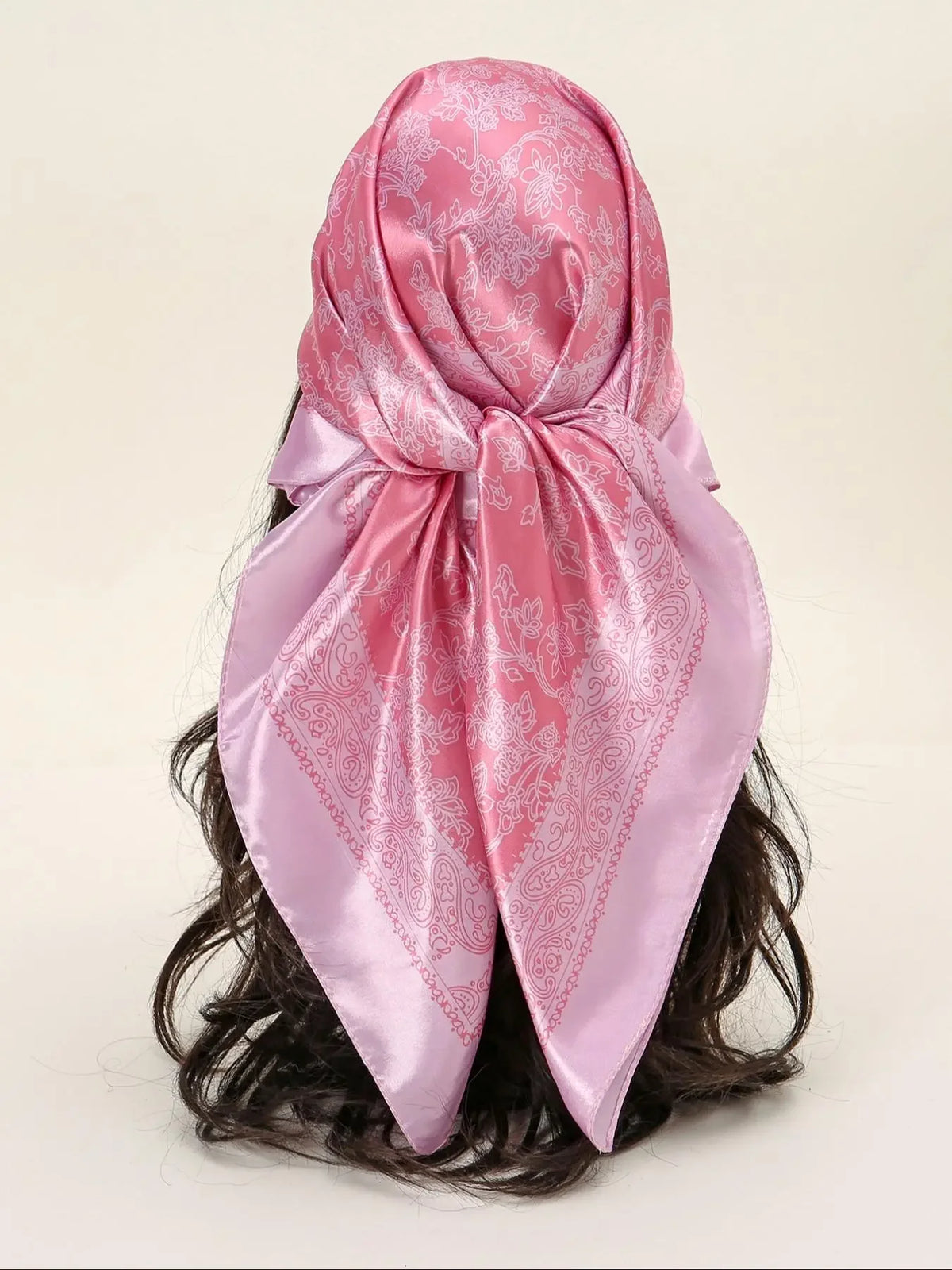 A pink floral satin shawl tied around a person's dark hair.