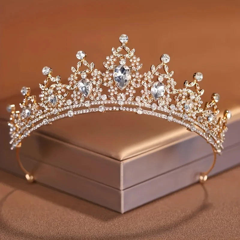 Diadema de cristal dorado brillante con intrincados diseños barrocos, mostrada en una caja.