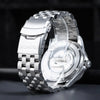 A close-up shot of an adjustable stainless steel watch featuring a textured metal band and a silver-toned watch case.