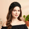 A woman models a black beaded headband with crystal pearls and floral accents against a light background.