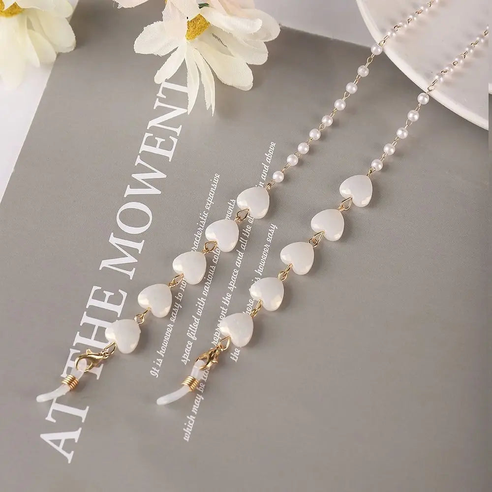 A delicate gold necklace featuring small white pearls and a pendant, displayed on a gray background.